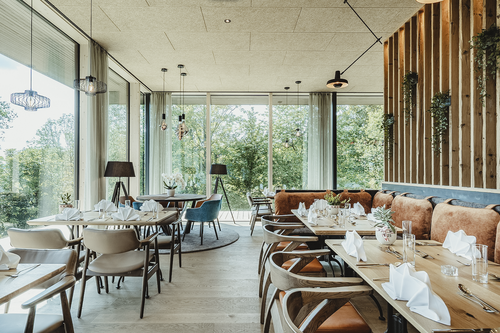 Großer heller Speisesaal im IKUNA Hotelrestaurant mit Blick ins Grüne.