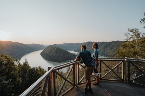 Zwei Radfahrer genießen den Blick über auf die Schlögener Schlinge der Donau.
