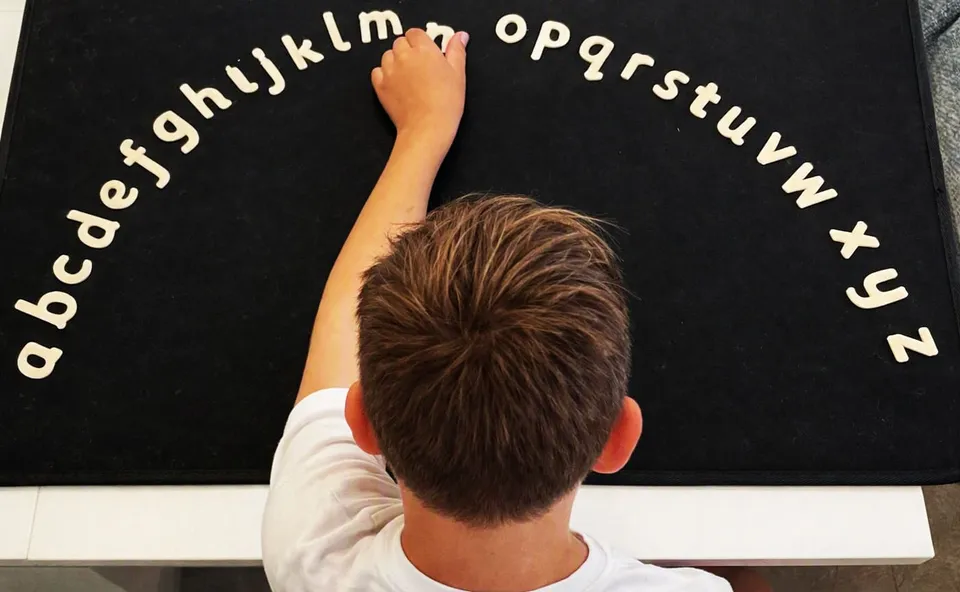 A pupil arranging wooden lowercase letters in an arc