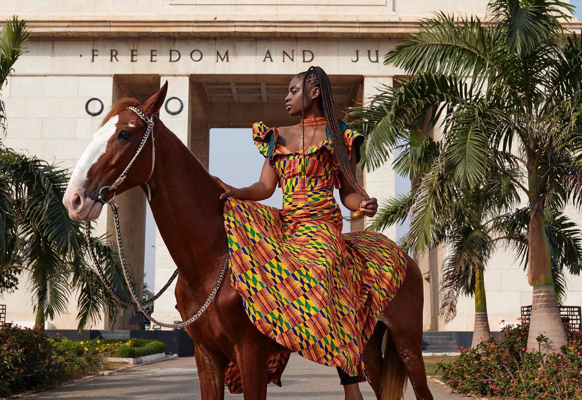 a diaspora standing in front of the independence arch in Accra