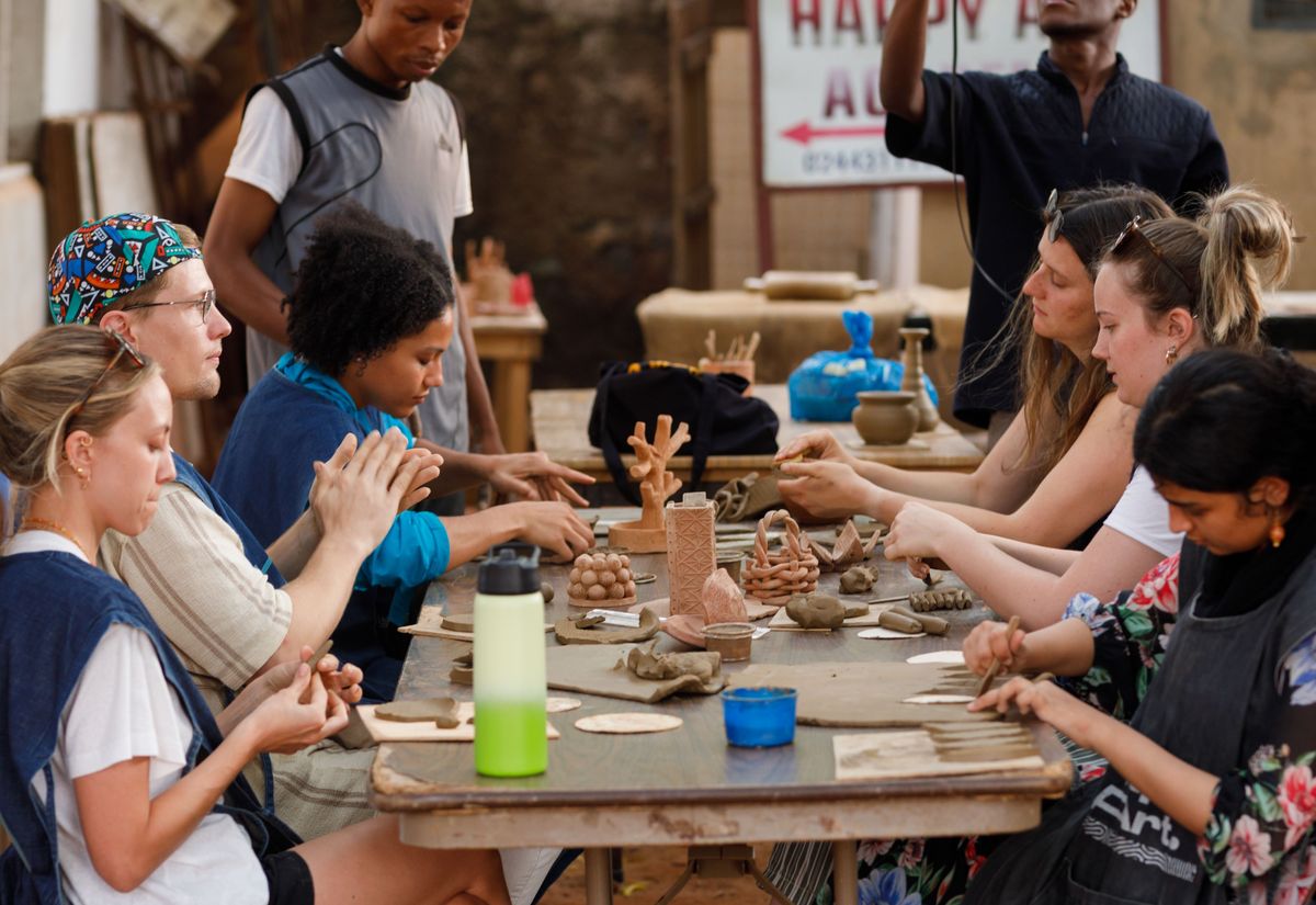Guests shaping clay around a workbench at the pottery workshop