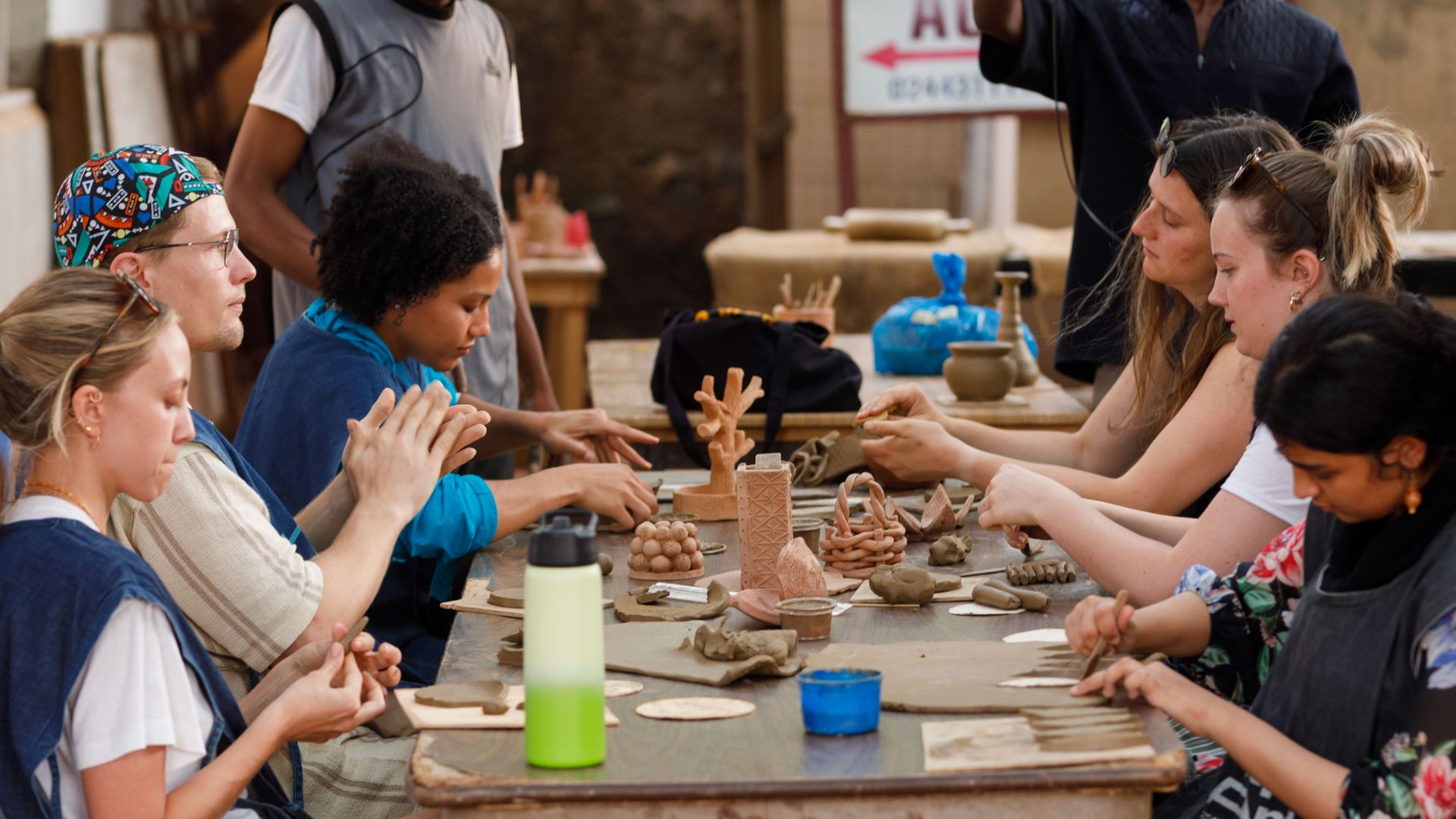 Guests shaping clay around a workbench at the pottery workshop