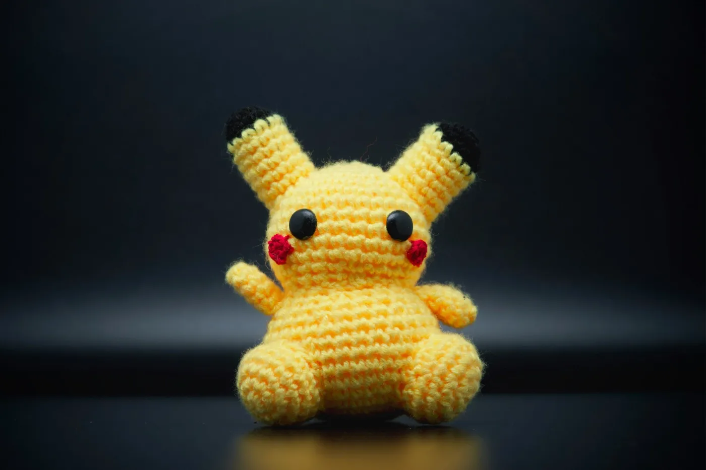 Een zelfgehaakte Pikachu op een donkere ondergrond