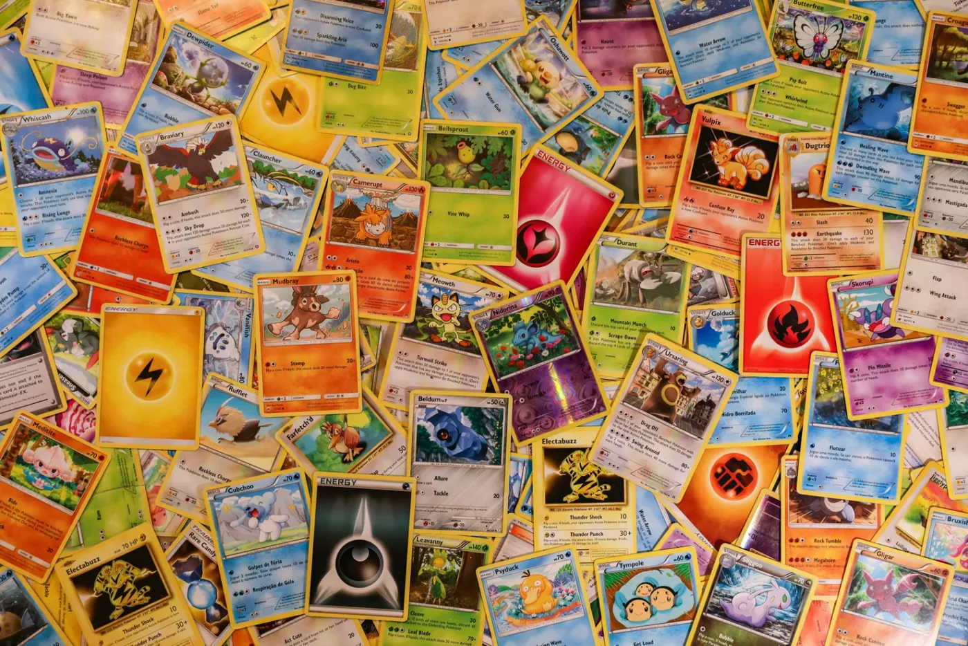 Grote stapel losse Pokémon-kaarten door elkaar, met gewone kaarten, energy cards en een reverse holo