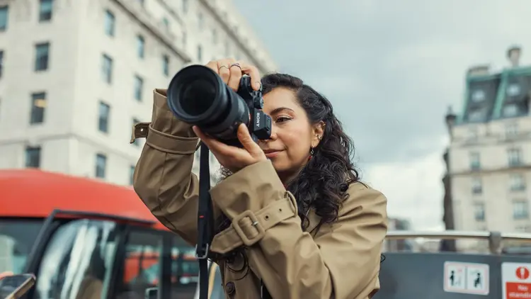 Woman taking a photograph with a camera on a city street