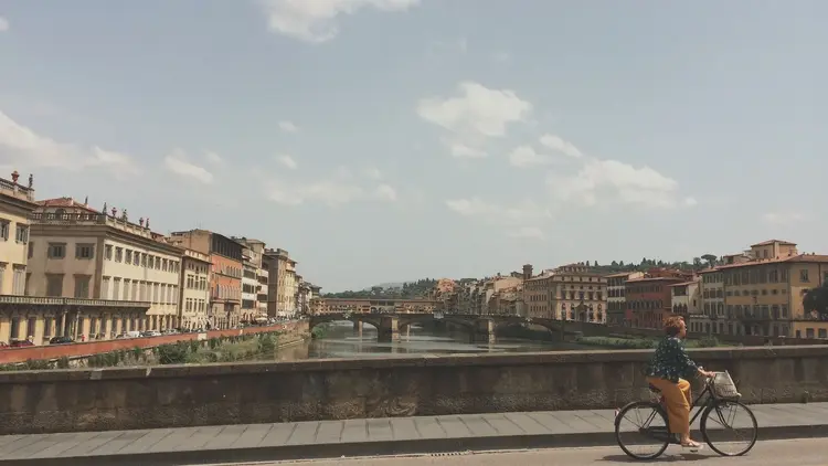 Cyclist pausing on a riverside bridge above a historic city