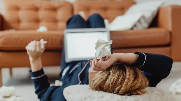Woman lying on the floor beside an open laptop, looking worn out