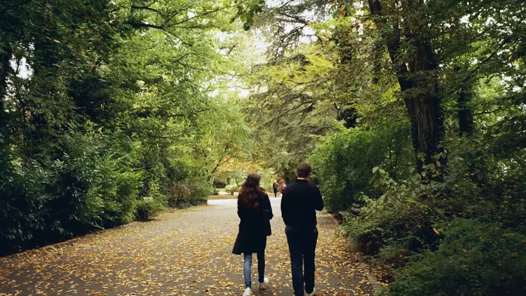 Couple walking along a leafy path through a green park