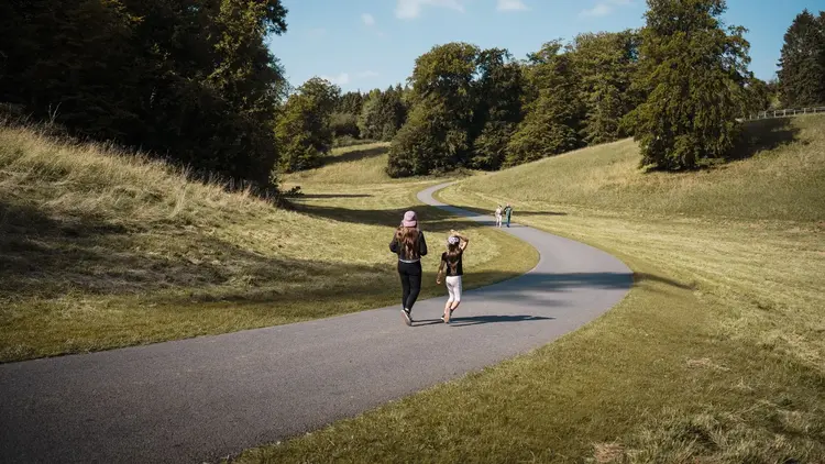 Two runners following a winding path through open parkland