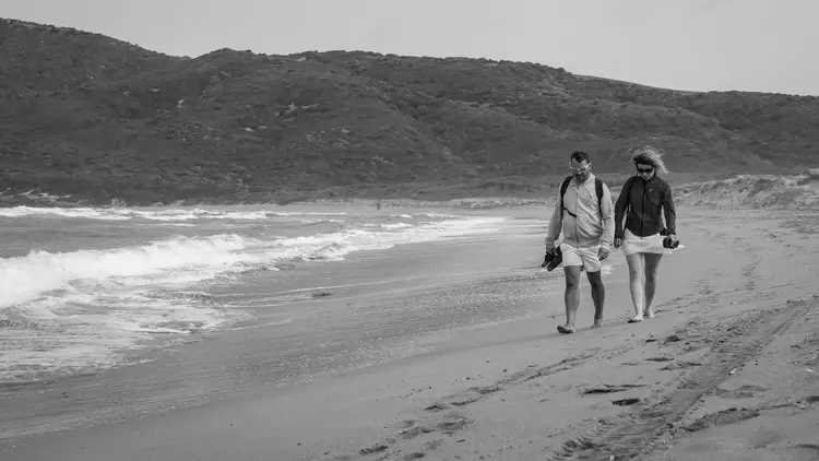 Black and white photograph of a couple walking along the shoreline