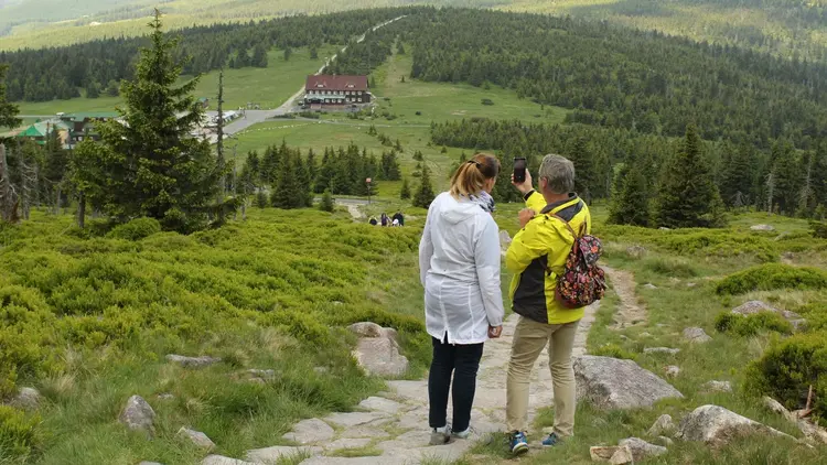 Two walkers pausing on a hillside path to look at the valley below