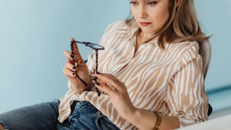 Woman examining a pair of glasses she is holding in both hands