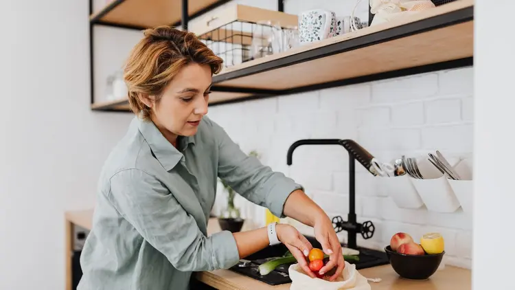 Woman preparing fresh fruit and vegetables at a kitchen worktop