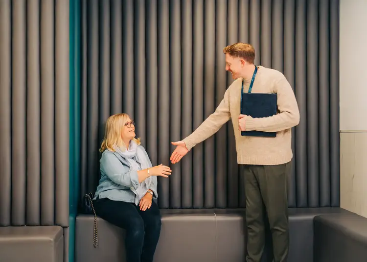 Optilase staff member with a folder shaking hands with a seated patient