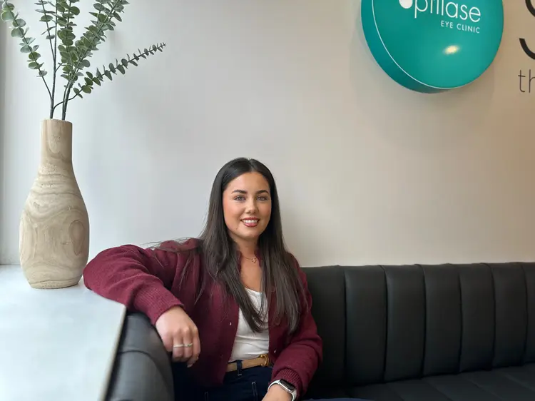 Smiling young woman seated in the Optilase Eye Clinic waiting area