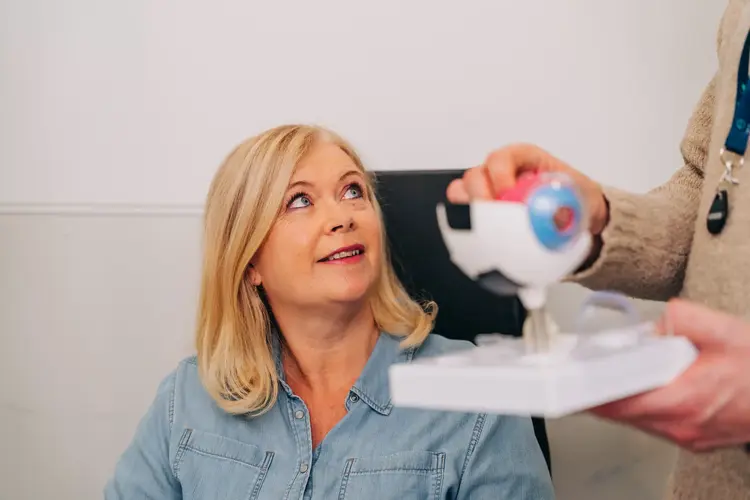 Optometrist showing a patient a model of the eye during a consultation