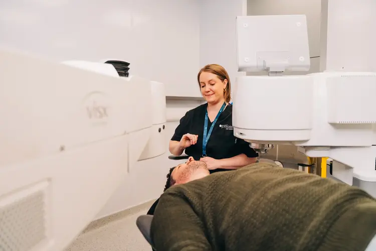 Clinician operating a VISX laser eye surgery machine over a patient