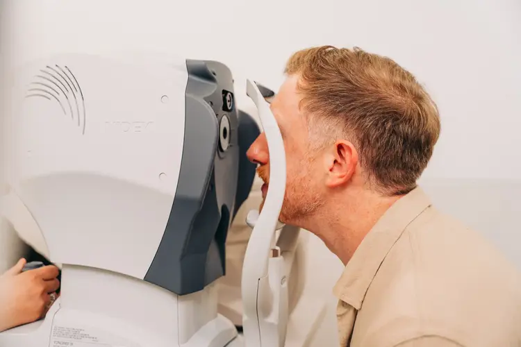 Man undergoing a machine eye examination during a consultation at Optilase.