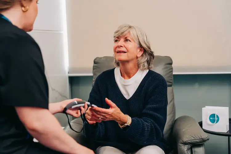 Elderly woman with gray hair talking to a healthcare professional about laser eye surgery aftercare.
