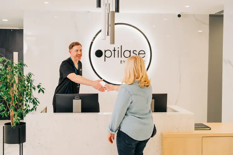 Optilase staff member greeting a patient with a handshake at reception