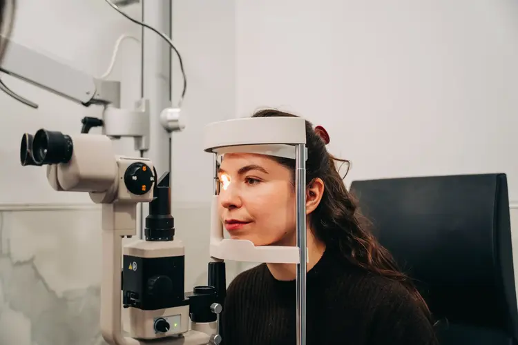 Young woman undergoing an eye examination with a slit lamp biomicroscope at Optilase Eye Clinic.