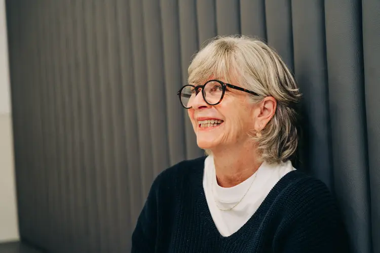 Smiling older woman with short grey hair and round glasses