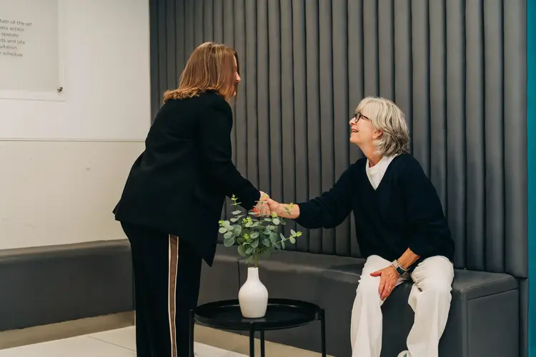 Optilase staff member shaking hands with a seated patient