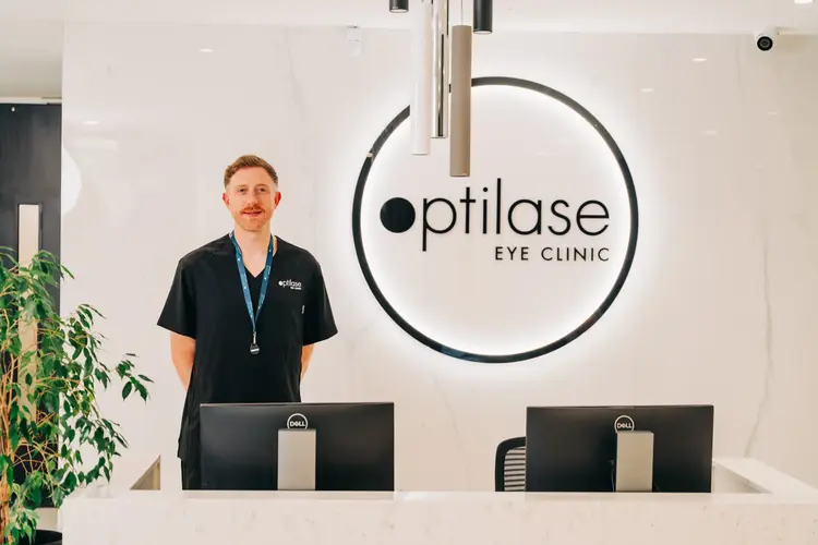 Optilase staff member at the reception desk, with the illuminated logo behind