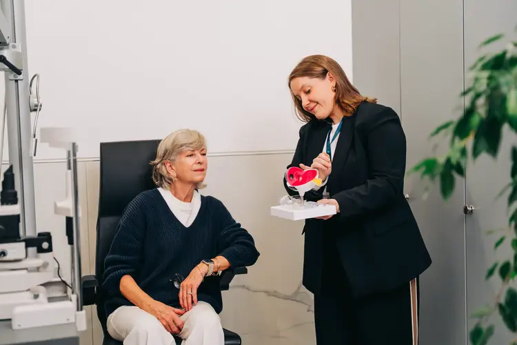 Optometrist showing an older patient a model of the eye at Optilase