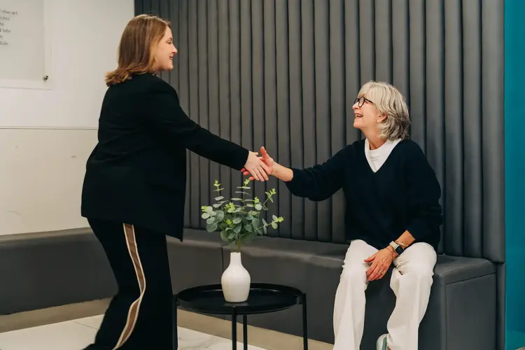 Two women shaking hands in the Optilase Eye Clinic reception