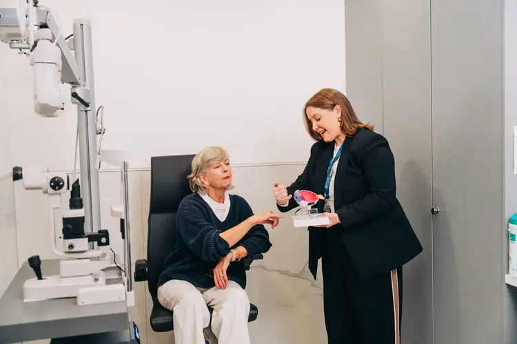 Optometrist showing an older patient a model of the eye at Optilase