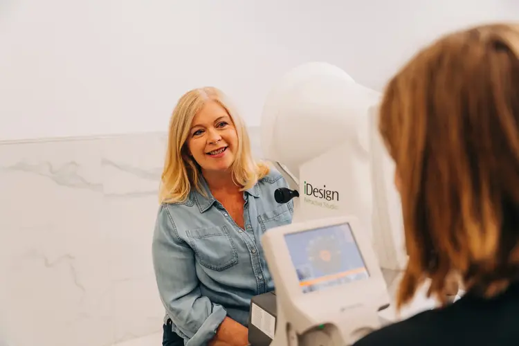 Smiling woman during an eye exam on an iDesign diagnostic machine