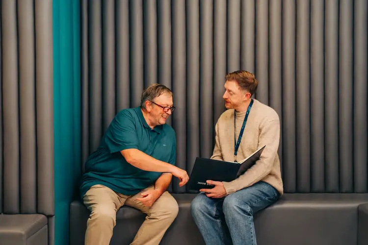 Two men on a sofa discussing eye exam results at Optilase
