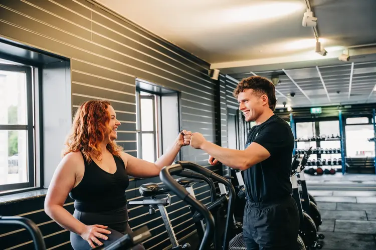 Woman fist-bumping her trainer at the gym after lens replacement surgery