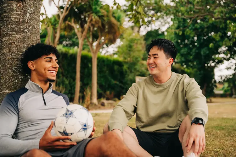 Two young men laughing outdoors with a football after LASIK
