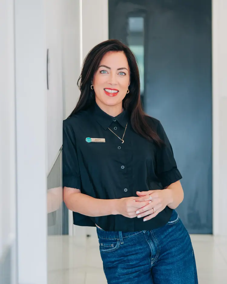 Smiling Optilase optometrist leaning against a white wall