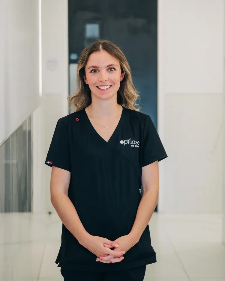 Smiling Optilase staff member in black scrubs in a clinic hallway