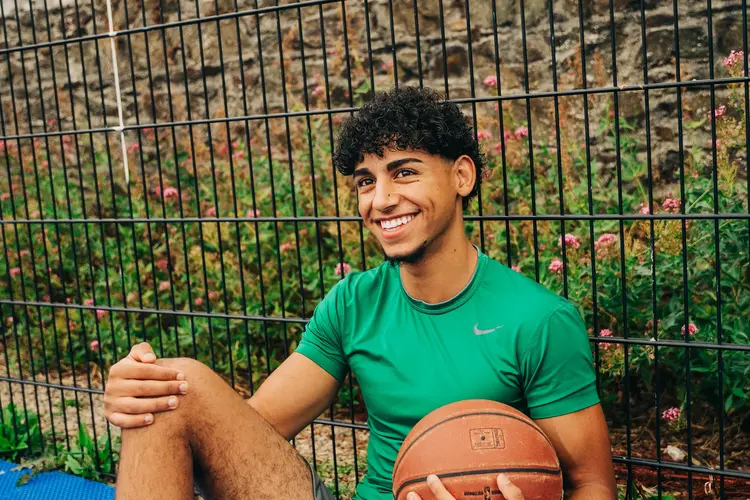 Young man with a basketball smiling outdoors after laser eye surgery