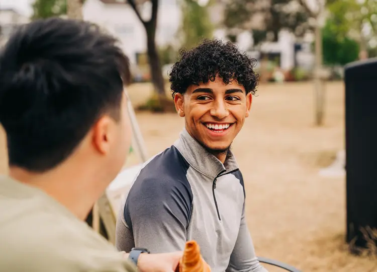 Young man laughing with a friend outdoors after laser eye surgery