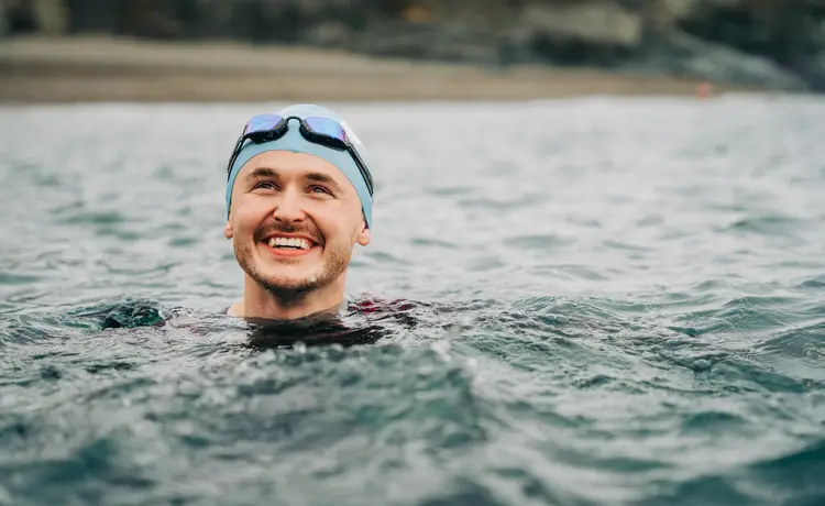 Smiling man swimming in the sea after PRK eye surgery