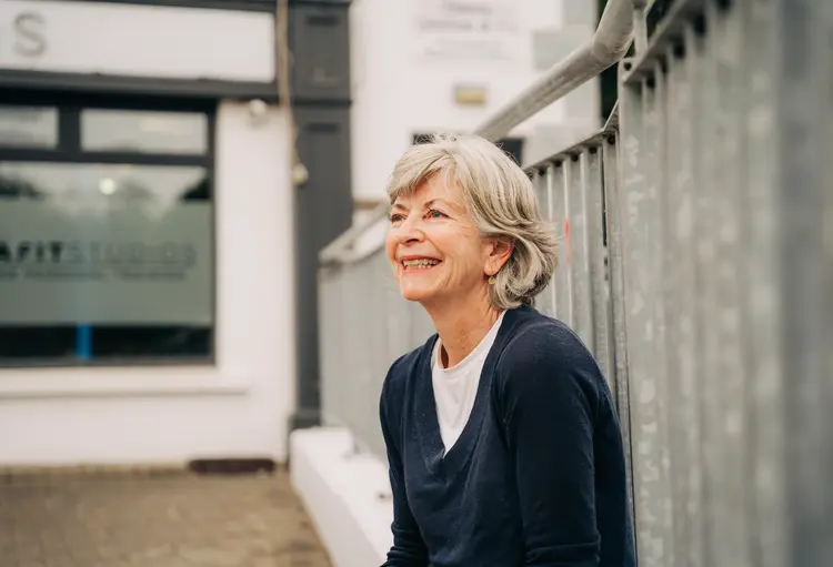 Smiling older woman sitting outdoors after her eye surgery