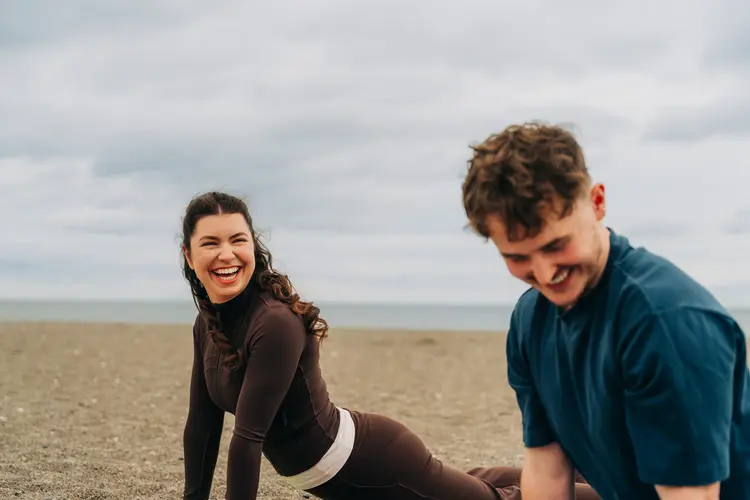 Two young people laughing together on a sandy beach