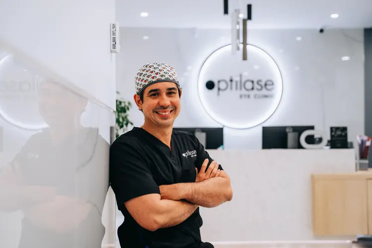 Smiling Optilase ophthalmologist in black scrubs and a surgical cap