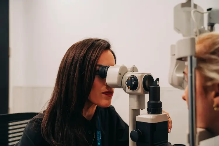 Woman looking into a slit lamp during an eye examination
