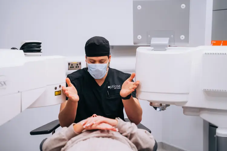 Clinician in a face mask explaining lens replacement surgery to a patient