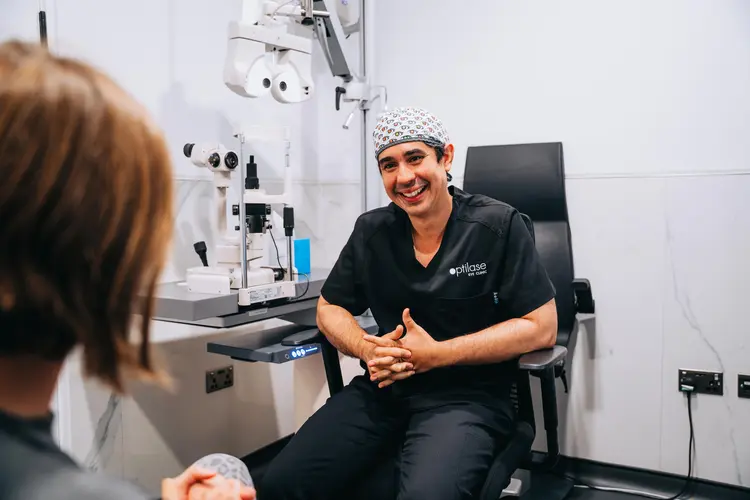 Smiling Optilase eye doctor consulting with a patient