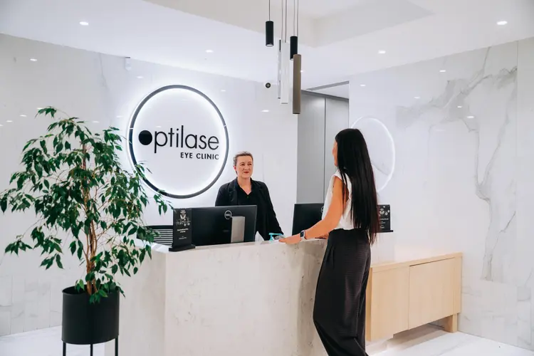 Two women at the marble reception desk of an Optilase Eye Clinic