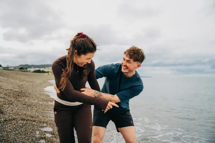 Two young people laughing together on a rocky beach