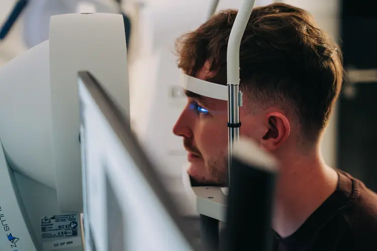 Young man undergoing an eye examination with a slit lamp machine ahead of his PRK eye surgery.