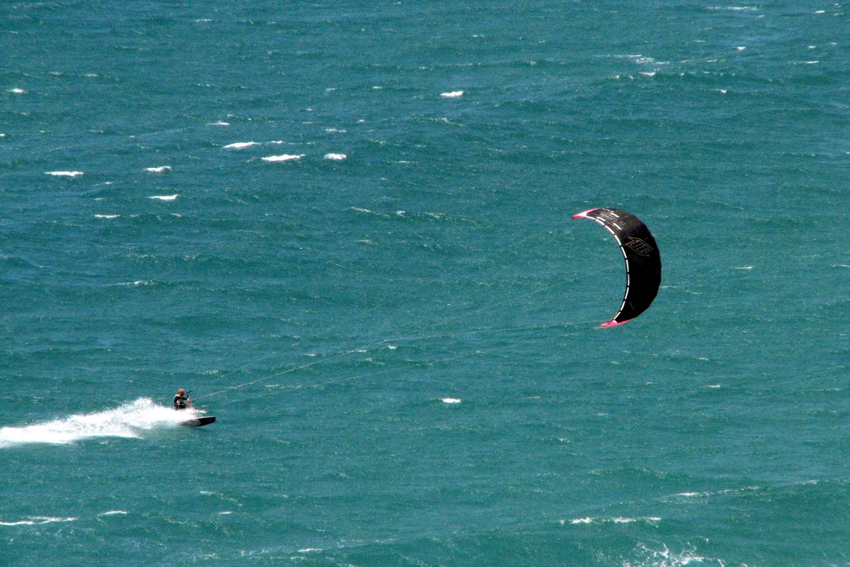 Kitesurfeur sur une mer verte et agitée au large de la forteresse de Sagres